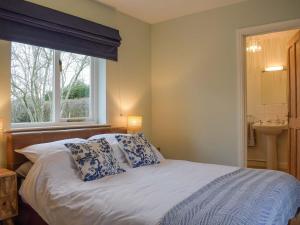 a bed with blue and white pillows and a window at Rose Cottage in Blakemere