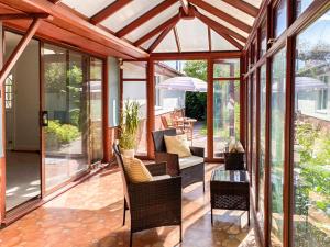 a conservatory with glass doors and chairs and a table at Rose Cottage in Blakemere