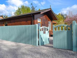uma casa de madeira com um portão e uma cerca em The Tranquil Orchard - Woodpecker-uk31339 em Mouswald