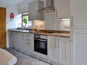 a white kitchen with white cabinets and a sink at The Tranquil Orchard - Woodpecker-uk31339 in Mouswald