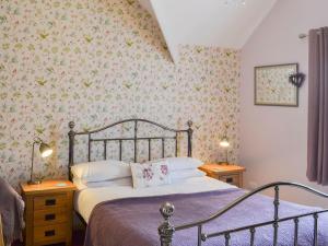 a bedroom with a bed with floral wallpaper at Forge Villa in Ebberston