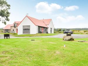 a white house with a red roof on a grass field at The Stable - Uk33400 in Isle of Gigha