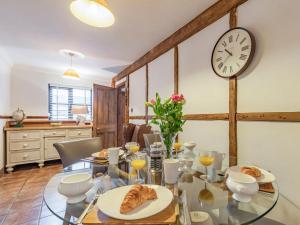 a dining room with a table with a clock on the wall at The Stables - Uk30946 in Barthomley