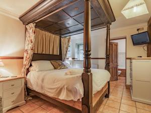 a bedroom with a four poster bed and a television at The Stables - Uk30946 in Barthomley