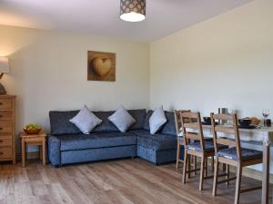 een woonkamer met een blauwe bank en een tafel bij The Stables At Greenview in Winsham