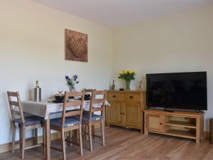 a dining room with a table and a flat screen tv at The Stables At Greenview in Winsham