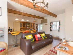 a living room with a leather couch and a kitchen at The Barn - Uk2475 in West Witton