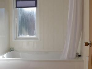 a white bath tub in a bathroom with a window at Lodge A- Uk33088 in Dinnet