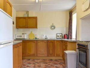 a kitchen with wooden cabinets and a microwave at Honeybags-uk12422 in Widecombe in the Moor