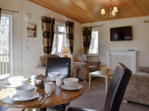 a living room with a wooden table and chairs at Lodge D- Uk33090 in Dinnet