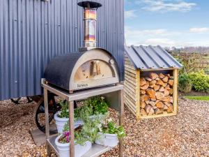 uma churrasqueira ao ar livre e uma casa com vasos de plantas em The Lambing Shed em Ryhill