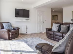 sala de estar con 2 sillas de cuero y TV de pantalla plana en Caddie - Uk11038 en Carlyon Bay
