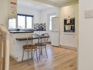 una cocina con electrodomésticos blancos y 2 sillas. en Caddie - Uk11038 en Carlyon Bay