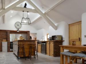 a large kitchen with white walls and wooden cabinets at Black Lion Folly in Rhydymwyn