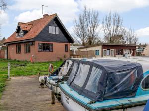 un bateau garé sur un quai devant une maison dans l'établissement Riverside Cottage, à Loddon