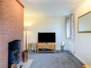 a living room with a fireplace and a television at Riverside Cottage in Loddon
