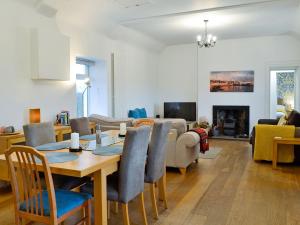 uma sala de jantar e sala de estar com mesa e cadeiras em Kirklauchline Cottage em Portpatrick