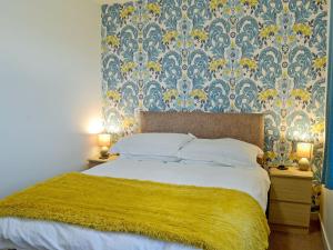 um quarto com uma cama grande e um cobertor amarelo em Kirklauchline Cottage em Portpatrick