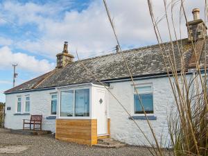a white cottage with a bench in front of it at Kirklauchline Cottage in Portpatrick