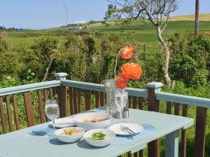 uma mesa azul com taças de comida e taças de vinho em Kirklauchline Cottage em Portpatrick