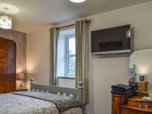 a bedroom with a bed and a television on the wall at Elderberry Cottage in Carnbrea