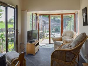 uma sala de estar com cadeiras e uma televisão e portas de vidro deslizantes em Borran Annexe em Colton
