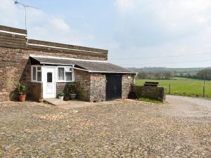 a stone house with a white door and a gravel driveway at The Dairy Barn in Burlescombe