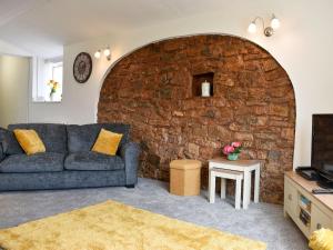 a living room with a couch and a brick wall at The Dairy Barn in Burlescombe