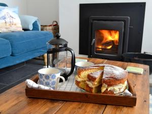 a table with a cake and two cups and a fireplace at Morolwg in Borth