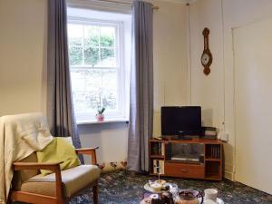 a living room with a tv and a chair at Number 4 in Llandeilo