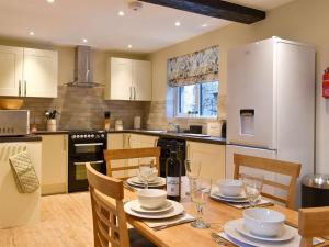 cocina con mesa con sillas y nevera blanca en May Cottage - Uk12970, en Settle