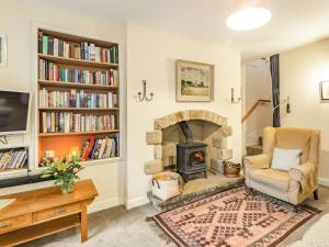 sala de estar con chimenea y silla en Garsdale Cottage, en Grassington