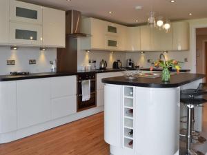 a kitchen with white cabinets and a black counter top at Quay House in Burton