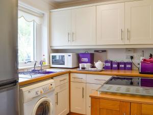 a kitchen with white cabinets and a washer at Seaview Cottage in Bonnavoulin
