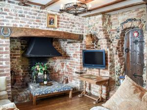 a living room with a brick wall with a fireplace at Canons Hall Cottage in Wingham