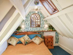 a bedroom with a bed with pillows on it at Canons Hall Cottage in Wingham