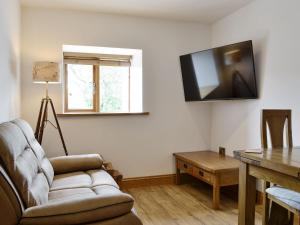 a living room with a couch and a television on the wall at The Byres Tethera in St Bees