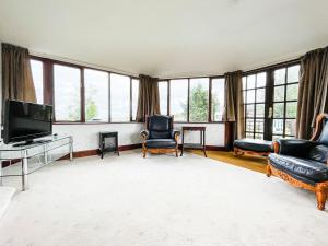 uma sala de estar com televisão, cadeiras e janelas em Fourpenny Studio - Uk34745 em Embo