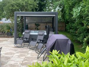 a patio with a table and chairs under a gazebo at Little Orchard in Worlington