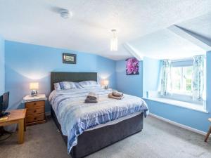 een blauwe slaapkamer met een bed en een raam bij Well Farmhouse - Uk11880 in North Tamerton