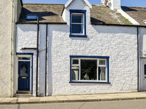 a white house with blue windows and a blue door at Hammys Cottage in Drummore