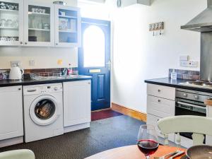 a kitchen with a washing machine and a blue door at Hammys Cottage in Drummore