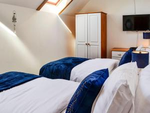 a bedroom with two beds with blue and white sheets at Hammys Cottage in Drummore