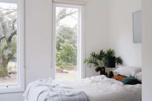 a white bedroom with a bed and a window at The Church at Lyonville - Daylesford Region in Lyonville