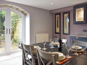 a dining room with a table with chairs and wine glasses at Thorneymire Cottage in Appersett