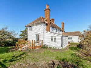 an old white house with two chimneys on a hill at Mark Farmhouse in Bradwell on Sea