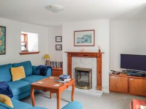 a living room with a blue couch and a fireplace at Needle Cottage in Cullen
