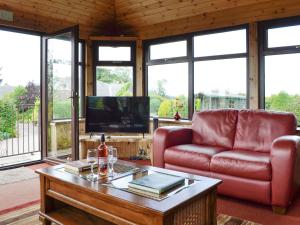 Sauchenshaw Cottage في Maryculter: غرفة معيشة مع أريكة حمراء وطاولة قهوة