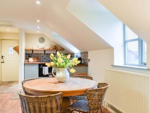 una cocina con una mesa con sillas y un jarrón de flores en Larkhams Loft en Teffont Magna