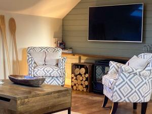 a living room with two chairs and a tv at Larkhams Loft in Teffont Magna